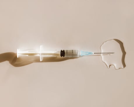 Syringe in puddle of vaccine<br>Top view of sterile syringe placed in puddle of transparent liquid drug on beige background