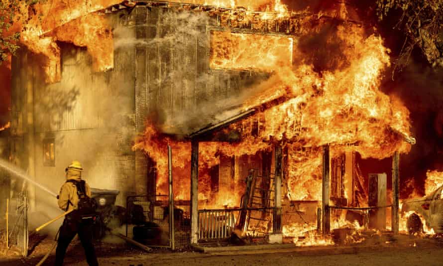 A firefighter sprays water while trying to stop the Sugar Fire, part of the Beckwourth Complex Fire, from spreading to neighboring homes in Doyle, California, on Saturday.