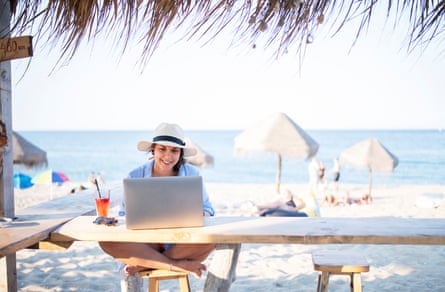 Shot of a woman sitting at a beach cafe and using a laptop.