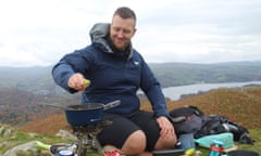 Harrison Ward squeezes a lime on Black Fell as he prepares cabbage and butternut squash sabzi, with Windermere in the background
