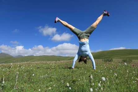 a woman does a cartwheel in a meadow.