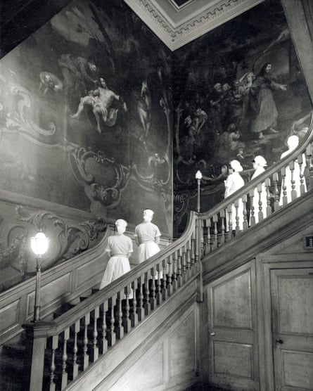 Historic black and white image of nurses standing on the staircase looking at the paintings