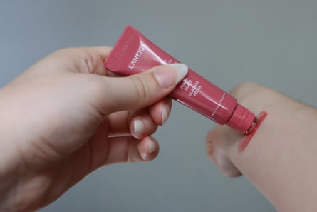 A woman tests a pink lip balm on her inner arm