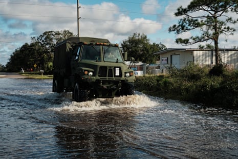 emergency vehicle drives through flood water in suburban area