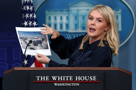 person wearing navy holds image while speaking behind podium