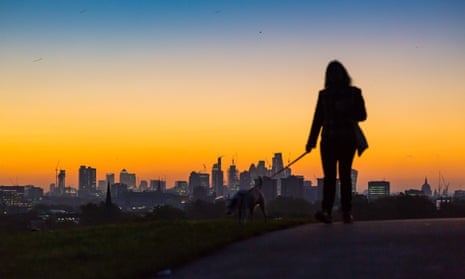 A woman watches sun rise over London’s skyline.