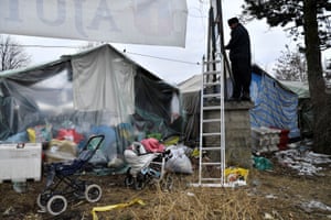 Romanian Orthodox monk, Father Modest, fixes the rope of a banner beside their hospitality tents in Siret, Romania, 13 March. Orthodox monks have a permanent presence at the Siret border providing food, clothes, supplies and accommodation to refugees who have fled Ukraine amid Russia’s invasion