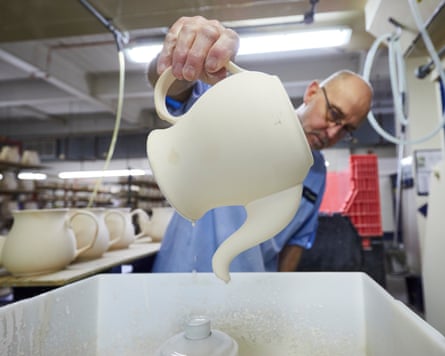 A worker applies a fountain rinse to a Denby teapot.