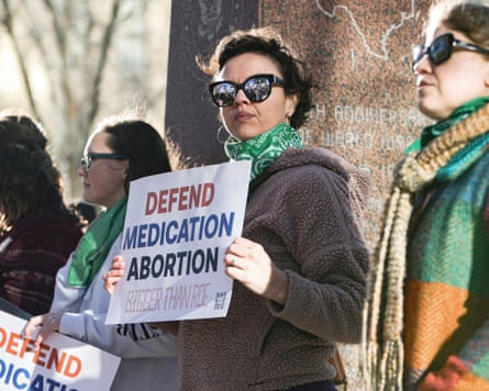 Lindsay London holds a protest sign reading 'Defend medication abortion, bigger than Roe' in front of a federal court building in Texas.