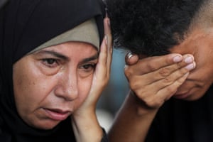 A woman crying next to a boy with his hand over his face