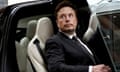 Elon Musk sitting in a Tesla car with the door open