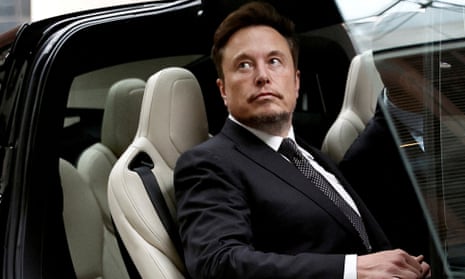 Elon Musk sitting in a Tesla car with the door open