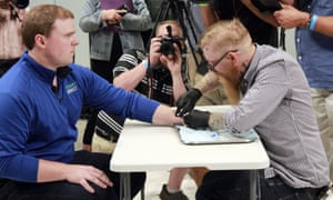 Tony Danna, vice president of Three Square Market in River Falls, receives a microchip in his left hand.