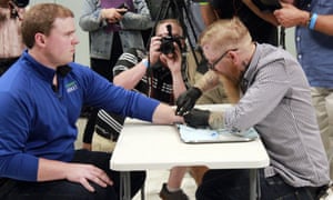 Tony Danna, left, vice president of international development at Three Square Market, receives a microchip in his left hand at company headquarters