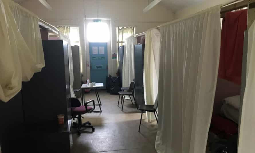 An old barracks with curtains dividing the cubicles containing the beds.