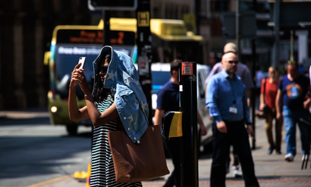 A woman in Manchester uses her jacket to shield her head and face from the sun