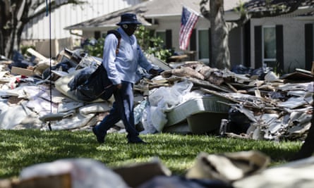 Postal worker Lonzell Rector makes his rounds among flood damaged debris from homes that lines the street in the aftermath of Hurricane Harvey in Houston.