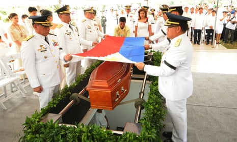 Military officers prepare to place a national flag on the coffin of the late dictator Ferdinand Marcos during the burial of Marcos at the heroes’ cemetery in Manila.