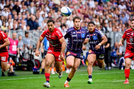 Bordeaux’s Damian Penaud runs alongside Dimitri Delibes of Toulouse with both players focused on a rugby ball.