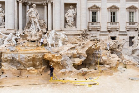 A man works in the drained pool of the fountain.