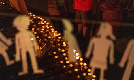 People standing next to dozens of candles with childish cutouts seen hanging from string