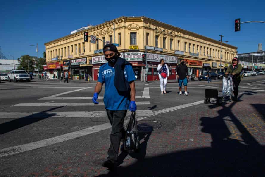 LA 맥아더 공원 지역의 길을 건너는 라틴계 노동자가 마스크와 장갑을 끼고있다.