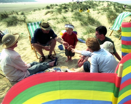 Six people sat around within colourful windbreak