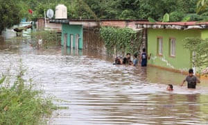 Inhabitants walk along a road flooded by the passage of Hurricane Willa in the town of Tecuala, Nayarit state, Mexico