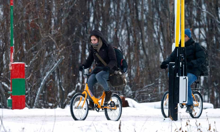 Two refugees cross the border between Norway and Russia on bicycles.