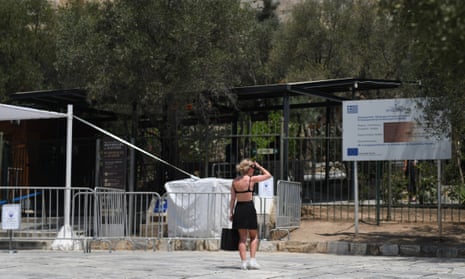 A woman looks at the Acropolis as it is closed during a heatwave in Athens, Greece