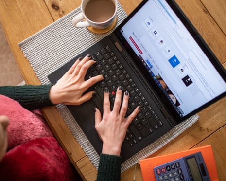 A woman is seen using a laptop on a dining room table set up as a remote office to work from home.