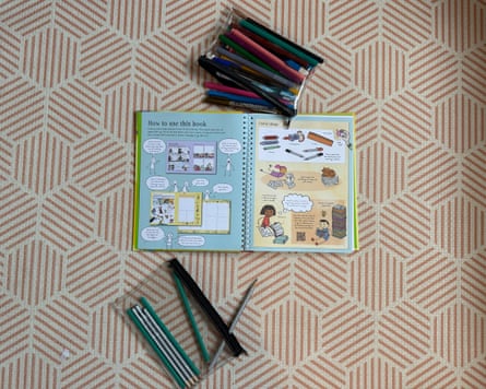 An open spiral-bound comic-making book lies surrounded by pencils and felt pens, from a children’s gift test