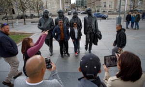 Tourists pose for pictures next to the statue of The Beatles in the Waterfront area.