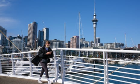 A masked woman walks over a bridge in Auckland, New Zealand.