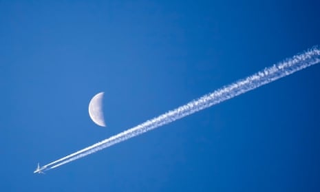 Plane flying past moon with bright blue sky