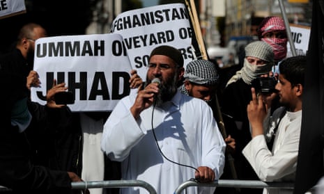 Bearded man talking into a microphone surrounded by banners