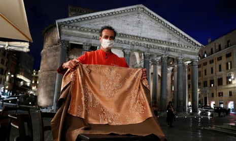 A waiter removes a table as he prepares to close a bar in front of the Pantheon in Rome.