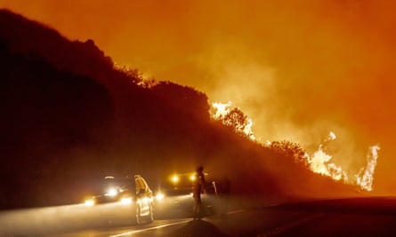 Vehicles are pulled off to the side of the road as the Bond Fire, driven by high winds, approaches Santiago Canyon Road in California on Thursday.