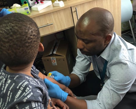 African doctor taking a blood sample from a young boy, face unseen