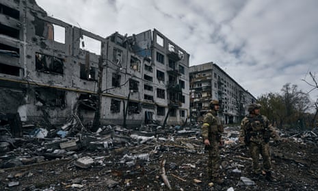 Ukrainian soldiers pass by houses ruined in the Russian shelling in Bakhmut.