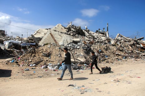 People walk past homes destroyed by Israeli airstrikes on 20 April 2026 in Gaza City.