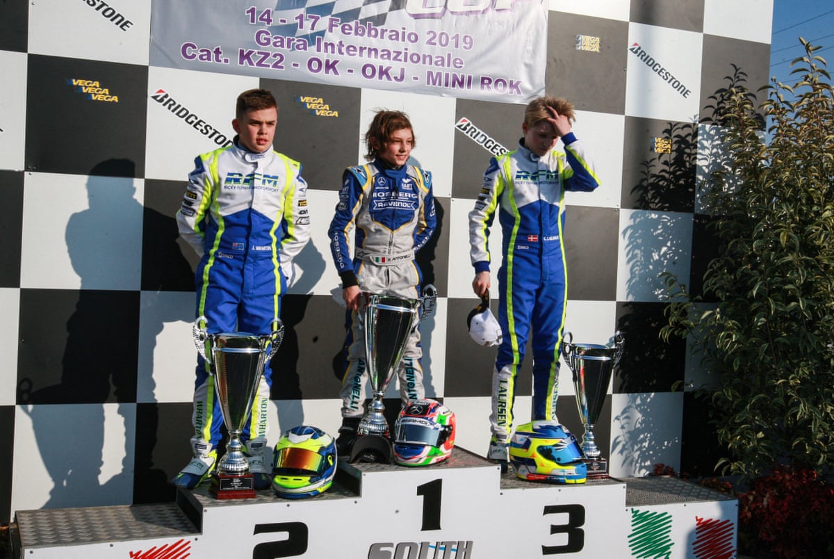 Andrea Kimi Antonelli stands atop a karting podium with trophies alongside two other young drivers