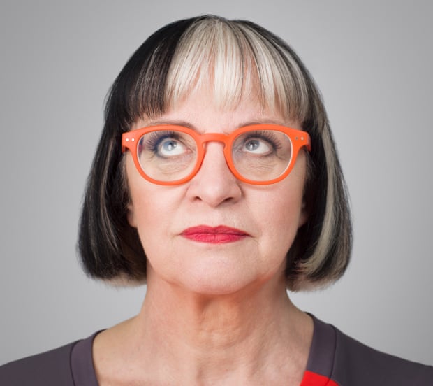 Close up of Philippa Perry in plastic orange-rimmed glasses and red lipstick, looking up