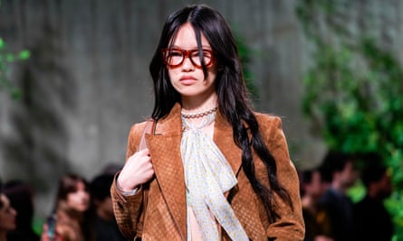 A model in a pussybow blouse, tan suede jacket and brown spectacles