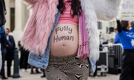 Young woman, marker ‘fully human’ on belly, pink clothes.