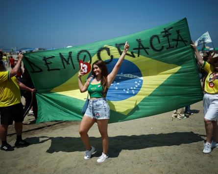 A smiling woman poses before a huge Brazilian flag reading