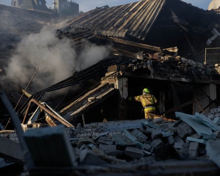 A firefighter puts out a fire a large, partly collapsed building