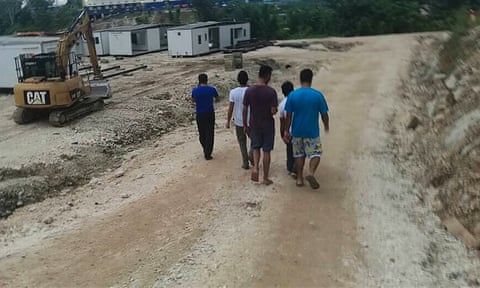 A group of refugees and asylum seekers walk by a construction site