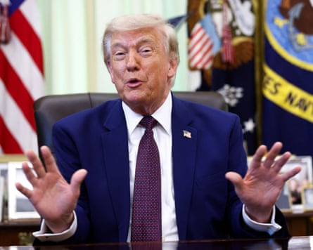 Donald Trump with his palms up sitting at the desk in the Oval Office.