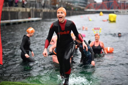 Woman in wetsuit gets out of the water at Salford. Others are in the water behind her